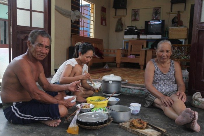 Vietnamese family eating dinner on the floor in the interior of their house.